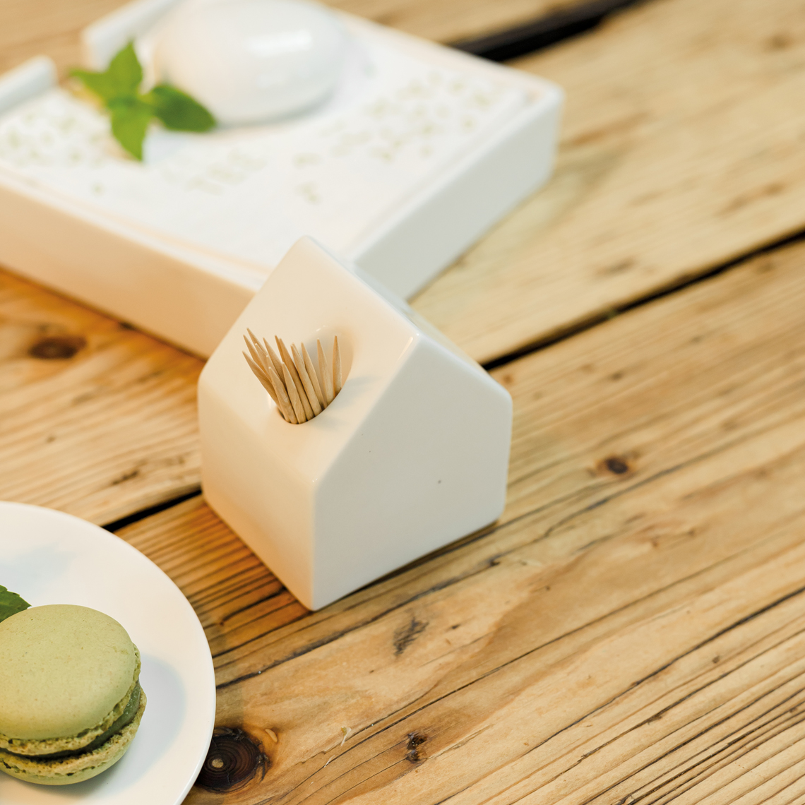 Zahnstocherhaus in Farbe weiß, Tafelgeschirr, Zahnstocherhalter, Zahnstocher, Macaron, Holztisch, Matcha-Macarons
